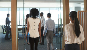 Rear View Of Businesspeople Entering Boardroom For Meeting