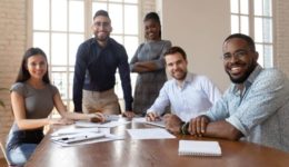 Portrait of happy diverse young businesspeople gather at boardroom table
