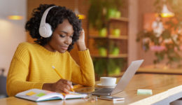 Smiling black girl with headset studying online, using laptop