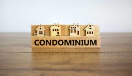 Block form the word condominium in front of a miniature house Block form the word condominium in front of a miniature house