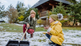 Boy with Down syndrome with his mother clearing snow from path with shovel in front of house.