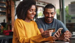 Man looking at his girlfriend shopping online in cafe