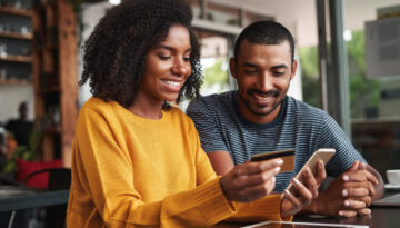 Man looking at his girlfriend shopping online in cafe