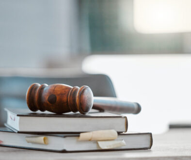 Justice, gavel and law books on table in office for court trial, legislation or fair constitution by judicial system. Firm, closeup and legal hammer by information for corporate case in workplace.