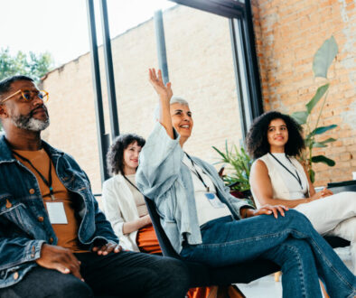 Diverse team brainstorming with a woman raising a question in an office meeting