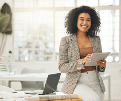 Happy businesswoman using a digital tablet. Young leading businesswoman using a wireless tablet. Creative designer working in her agency. Designer standing in her office using an online app