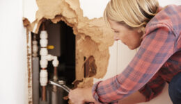 Middle aged woman repairing burst water pipe with a wrench