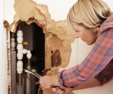 Middle aged woman repairing burst water pipe with a wrench